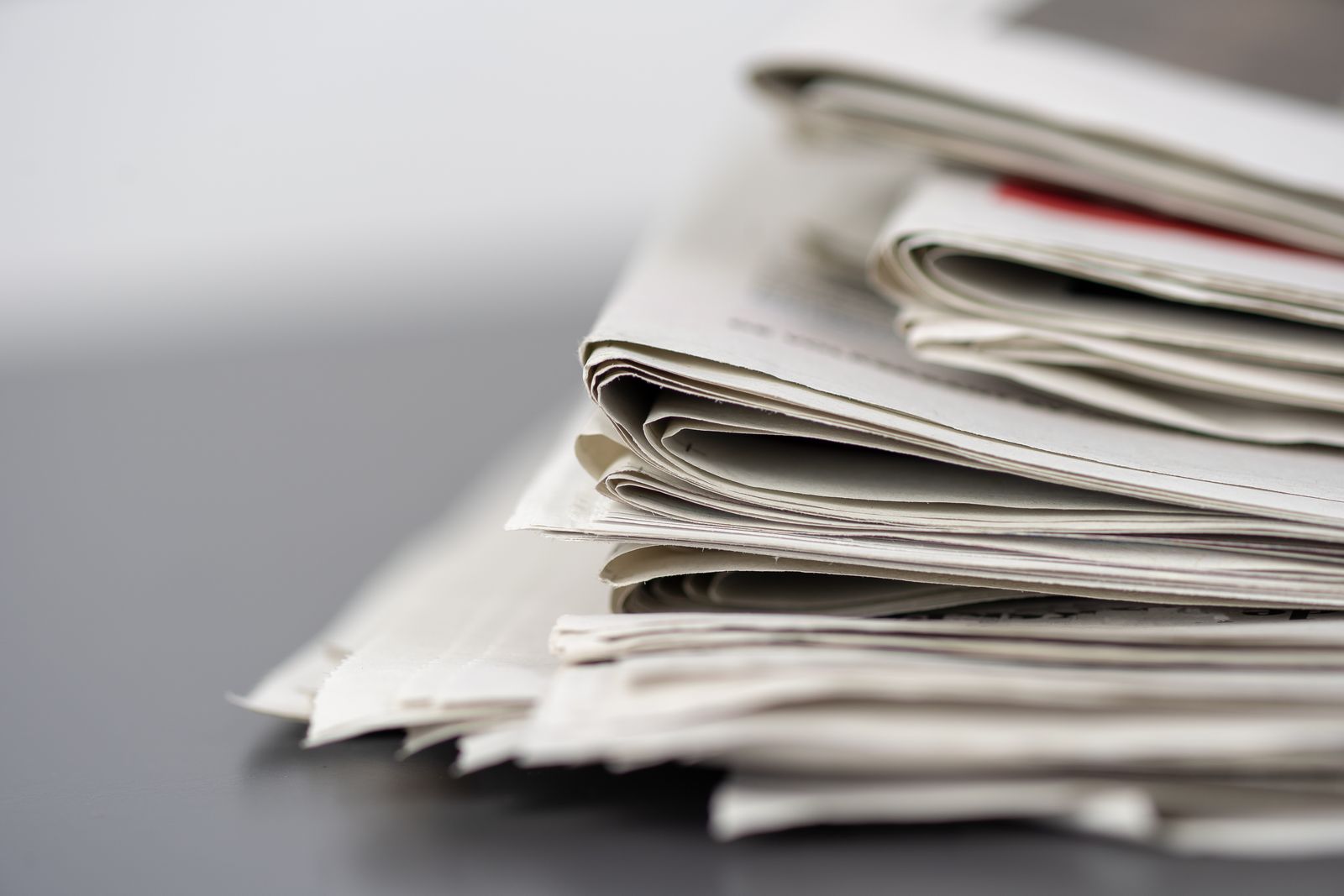 Gros plan de journaux empilés sur une table, représentant les médias et le journalisme.